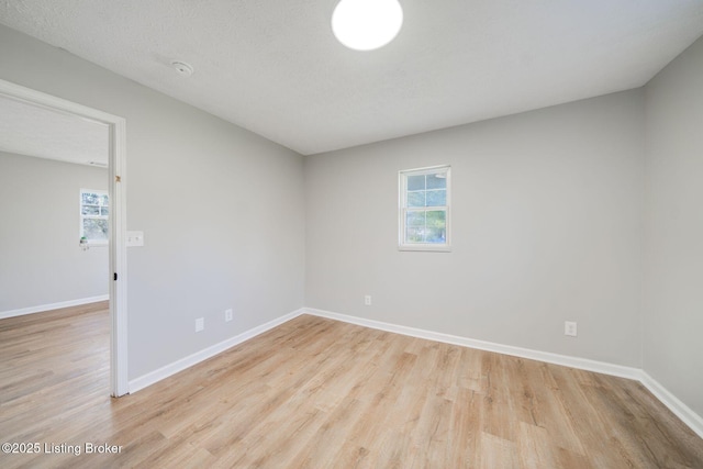 spare room featuring baseboards and light wood-style floors