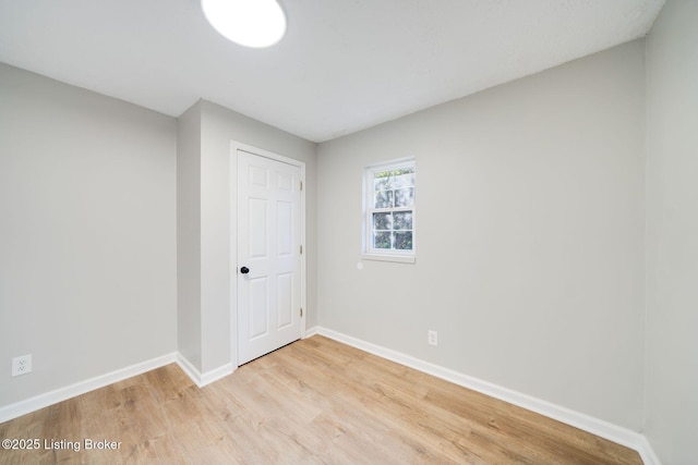 unfurnished room featuring baseboards and light wood finished floors