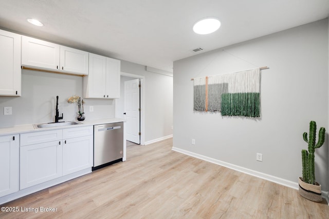 kitchen featuring light wood finished floors, light countertops, visible vents, stainless steel dishwasher, and a sink