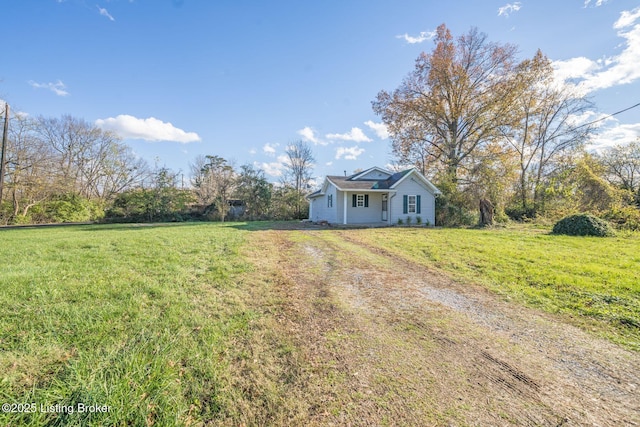 view of front of home with dirt driveway and a front yard