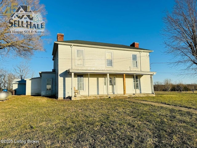 back of property with covered porch, a yard, and a chimney