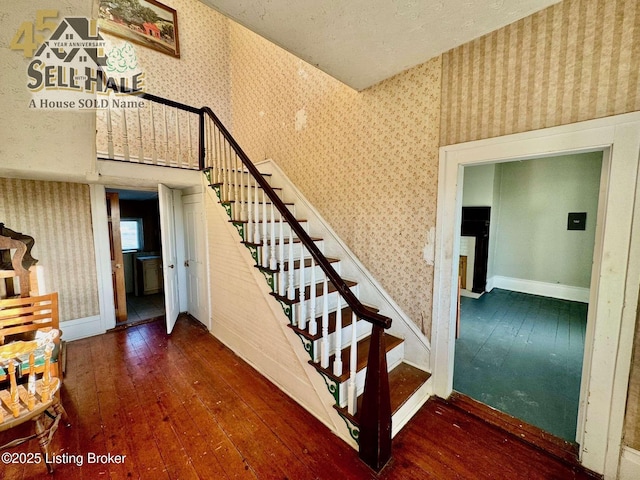 staircase with wallpapered walls, wood-type flooring, and baseboards