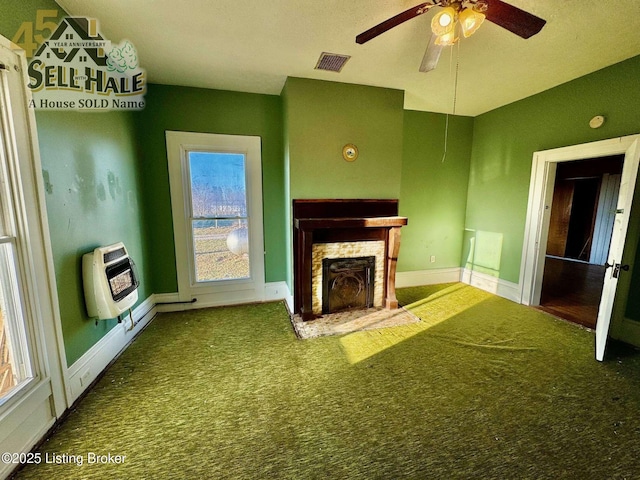 unfurnished living room featuring carpet floors, a fireplace, heating unit, visible vents, and baseboards