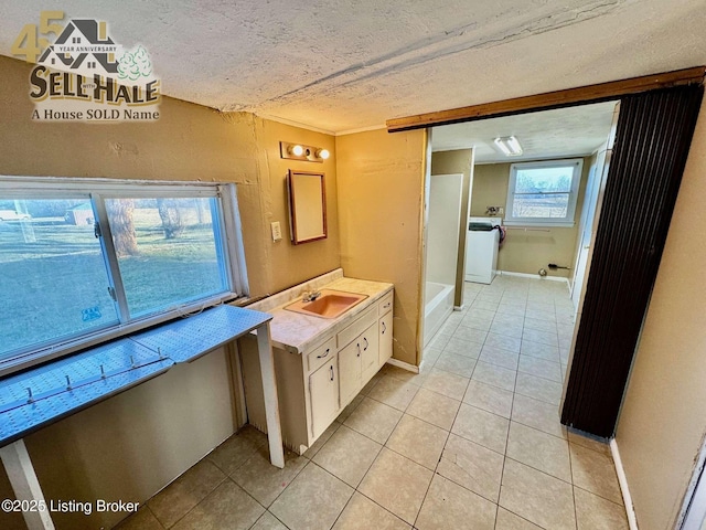 bathroom featuring a textured ceiling, washer / clothes dryer, and tile patterned flooring