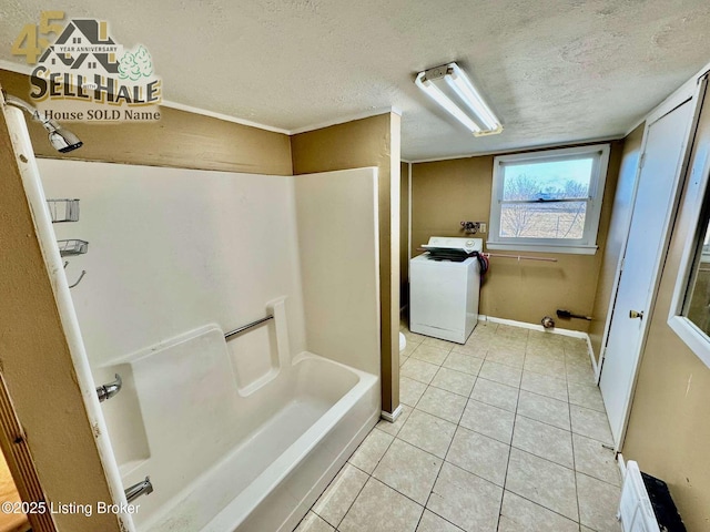 bathroom with a textured ceiling, bathing tub / shower combination, baseboards, tile patterned floors, and washer / clothes dryer