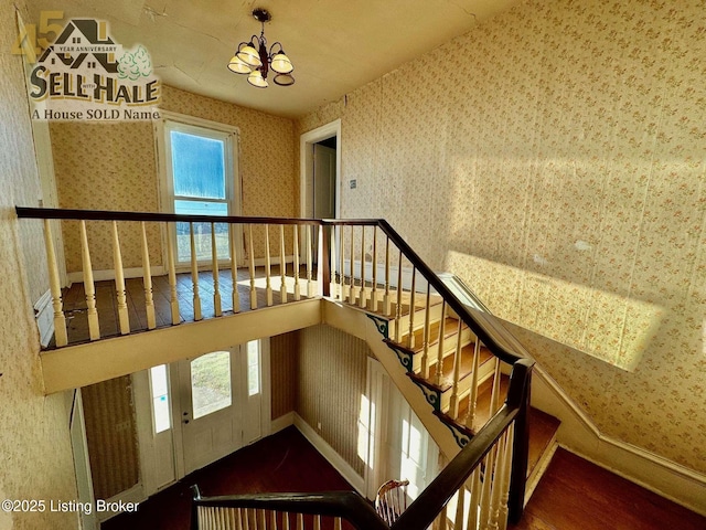 staircase featuring a chandelier, baseboards, wood finished floors, and wallpapered walls