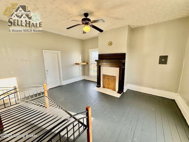 interior space featuring dark wood-style floors, ceiling fan, baseboards, and a tile fireplace