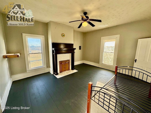 unfurnished bedroom with dark wood finished floors, multiple windows, a fireplace, and baseboards