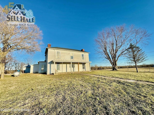 back of property with a yard and a chimney