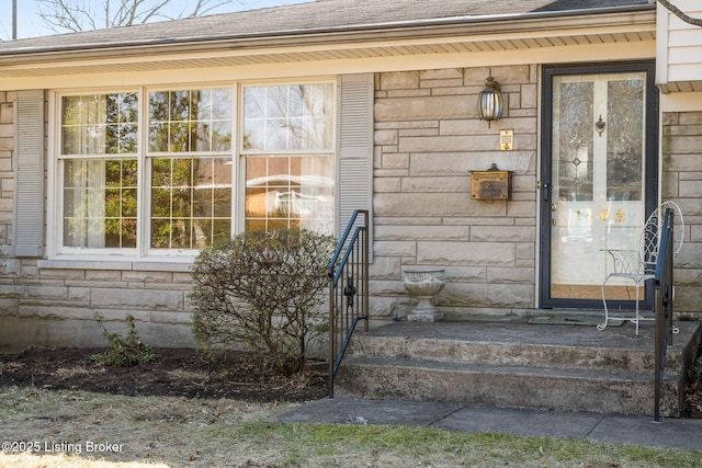 property entrance with stone siding and roof with shingles