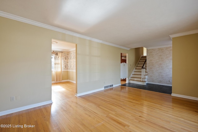 unfurnished room featuring baseboards, visible vents, wood finished floors, stairs, and crown molding