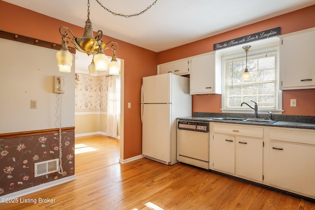 kitchen featuring white appliances, a sink, visible vents, light wood-style floors, and dark countertops