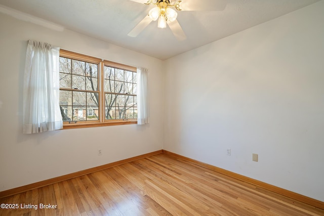 spare room featuring light wood finished floors, ceiling fan, and baseboards