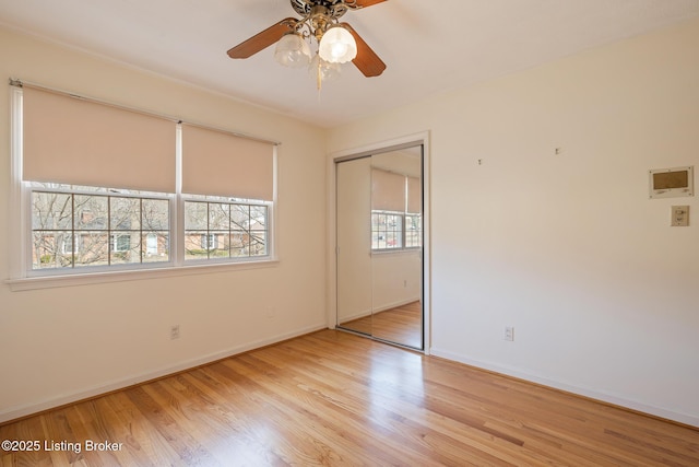 unfurnished bedroom with a ceiling fan, a closet, baseboards, and wood finished floors