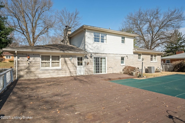 rear view of house with central AC unit, stone siding, a chimney, fence, and a wooden deck