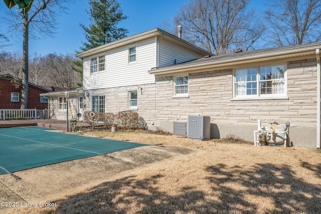 back of property featuring stone siding and cooling unit