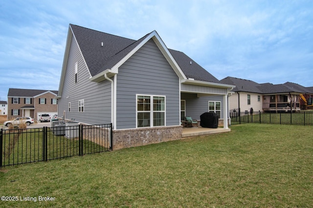 back of house featuring a patio, a lawn, brick siding, and a fenced backyard