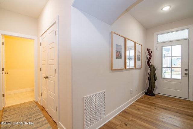 doorway to outside with baseboards, visible vents, and light wood-type flooring