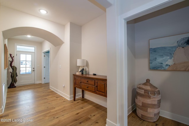 entrance foyer with recessed lighting, baseboards, arched walkways, and light wood-style floors