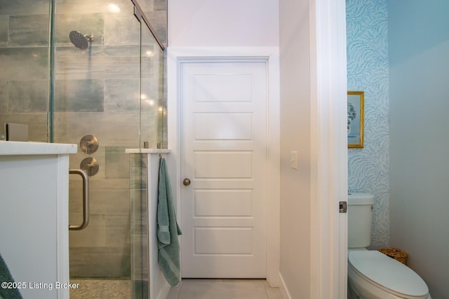 bathroom featuring a shower stall, wallpapered walls, and toilet