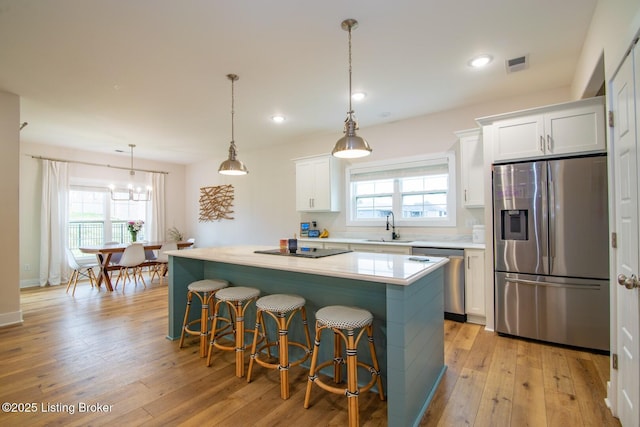 kitchen featuring visible vents, a sink, a center island, appliances with stainless steel finishes, and white cabinets