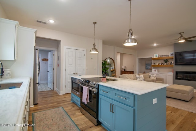 kitchen with visible vents, open floor plan, stainless steel appliances, white cabinetry, and blue cabinets