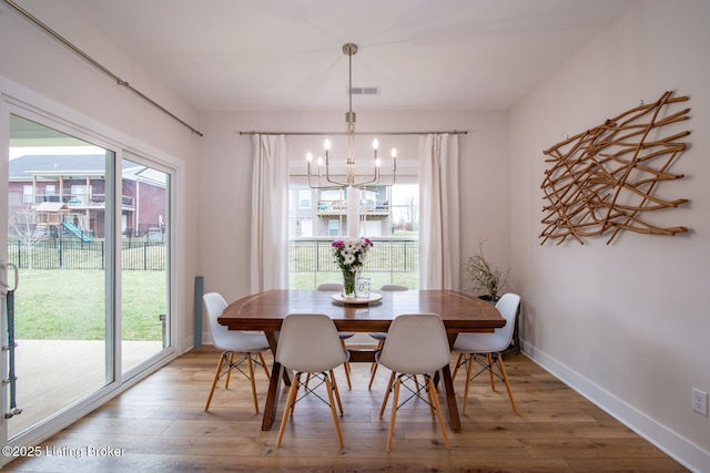 dining room featuring a chandelier, visible vents, baseboards, and wood finished floors