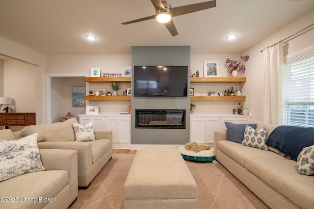 living room with light tile patterned flooring, a glass covered fireplace, recessed lighting, and a ceiling fan