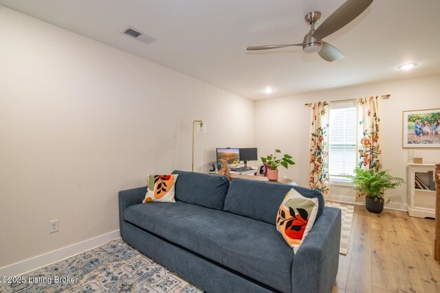 living area featuring a ceiling fan, visible vents, light wood-style floors, and baseboards