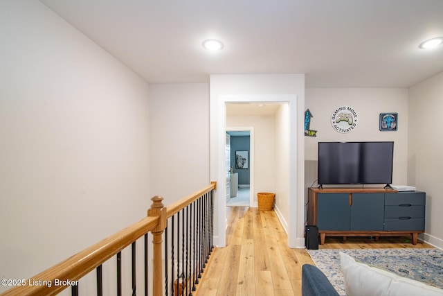 corridor featuring recessed lighting, an upstairs landing, light wood-style floors, and baseboards