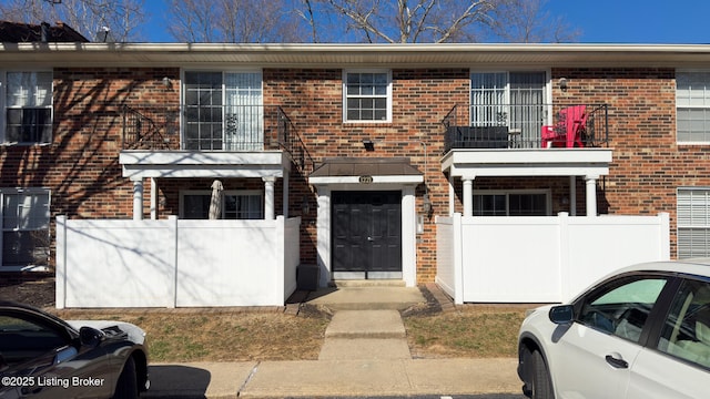 multi unit property with brick siding and a fenced front yard