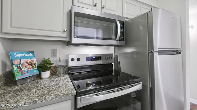 kitchen featuring stainless steel appliances, dark stone counters, and white cabinetry