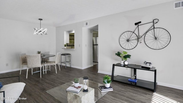 living area with baseboards, a notable chandelier, visible vents, and wood finished floors