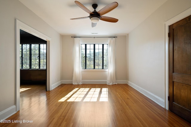 empty room featuring a ceiling fan, baseboards, and wood finished floors