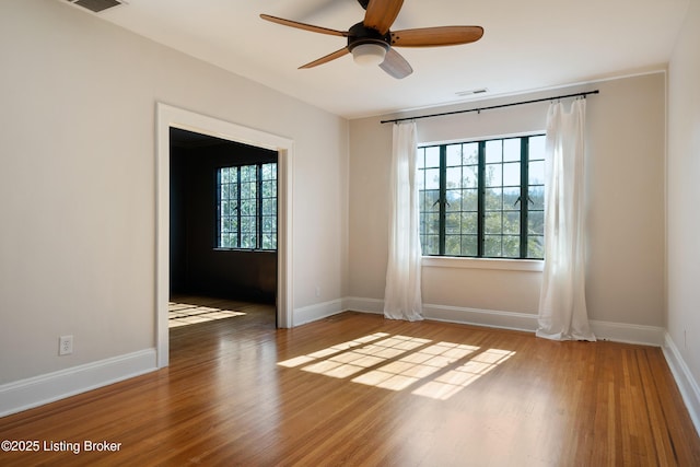 spare room featuring visible vents, baseboards, and wood finished floors