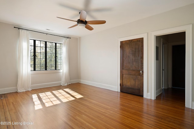 spare room featuring a ceiling fan, baseboards, visible vents, and wood finished floors