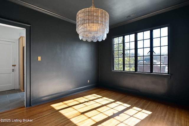 empty room featuring wood finished floors, visible vents, baseboards, ornamental molding, and an inviting chandelier