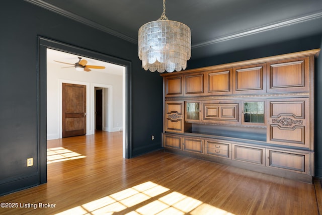 interior space with a chandelier, ornamental molding, wood finished floors, and baseboards