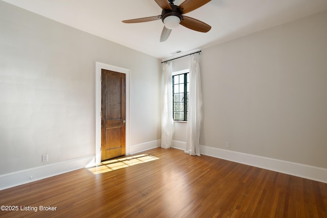 spare room with a ceiling fan, wood finished floors, visible vents, and baseboards