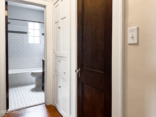 full bathroom with shower / washtub combination, toilet, and wood finished floors