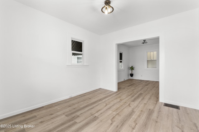 spare room with wood finished floors, visible vents, and baseboards