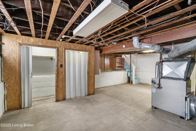 unfinished basement featuring stairway and heating unit