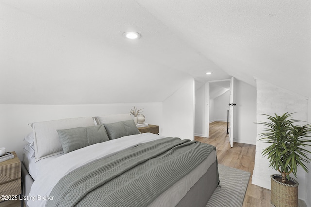 bedroom featuring lofted ceiling, a textured ceiling, light wood-type flooring, and recessed lighting