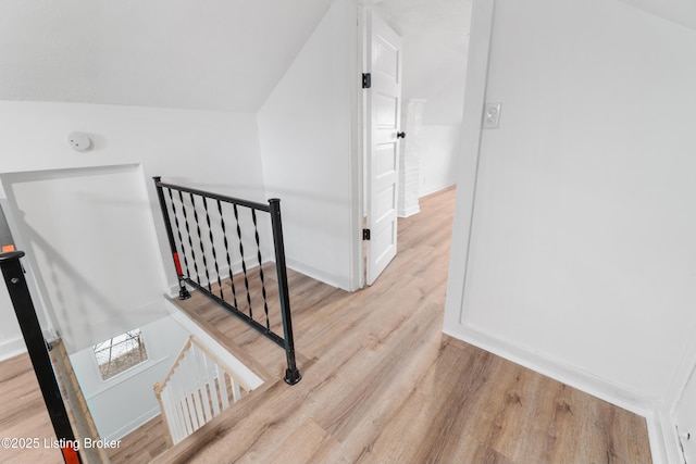 staircase featuring baseboards, vaulted ceiling, and wood finished floors