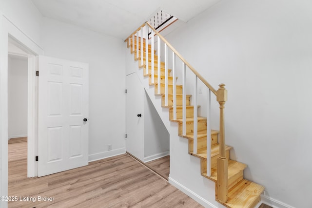 staircase with baseboards and wood finished floors