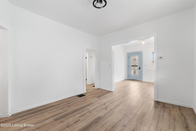 spare room featuring baseboards, visible vents, and wood finished floors