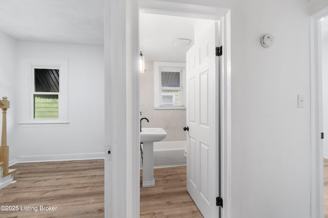 corridor with light wood finished floors, baseboards, and a wealth of natural light