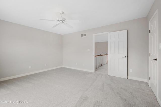 unfurnished room with a ceiling fan, light colored carpet, visible vents, and baseboards