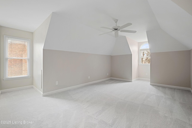 additional living space with light carpet, lofted ceiling, a ceiling fan, and baseboards