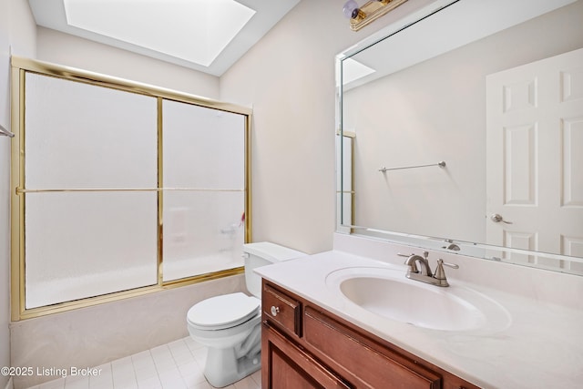 bathroom featuring a skylight, enclosed tub / shower combo, vanity, and toilet